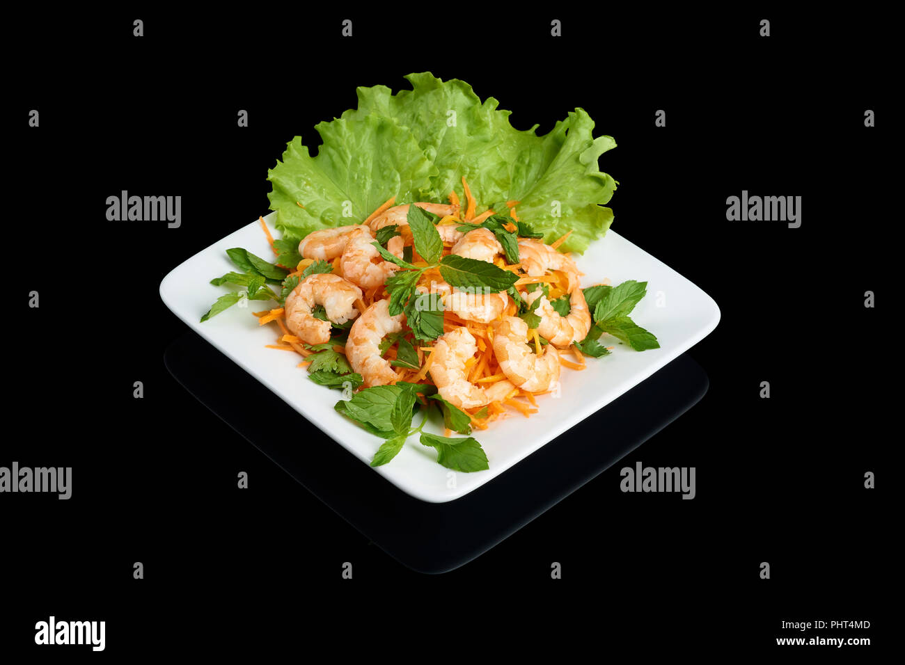 Vietnamese cuisine Mango salad with shrimps with vegetables on rectangular white plate isolated on black reflective background Stock Photo