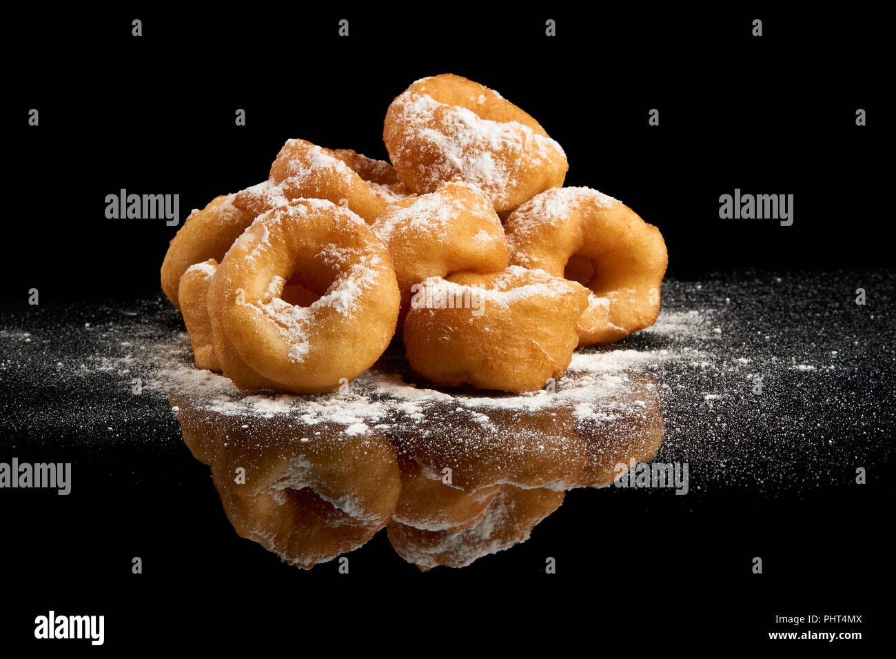 Heap of donuts with sugar powder on black reflective background Stock Photo