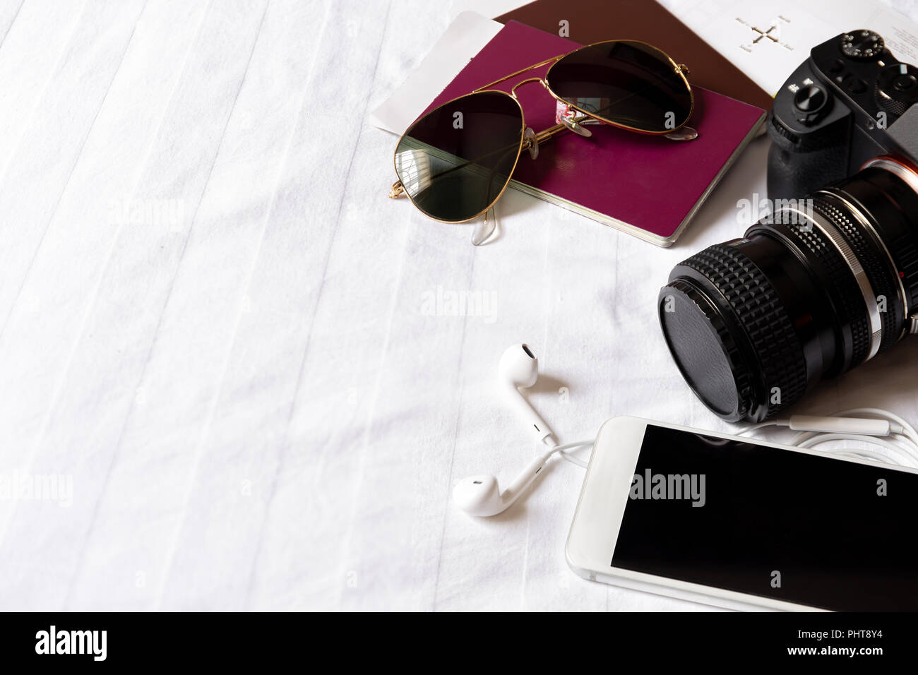 Top view of traveler accessories on the bed with digital camera, cellphone, sunglasses and passport. Stock Photo