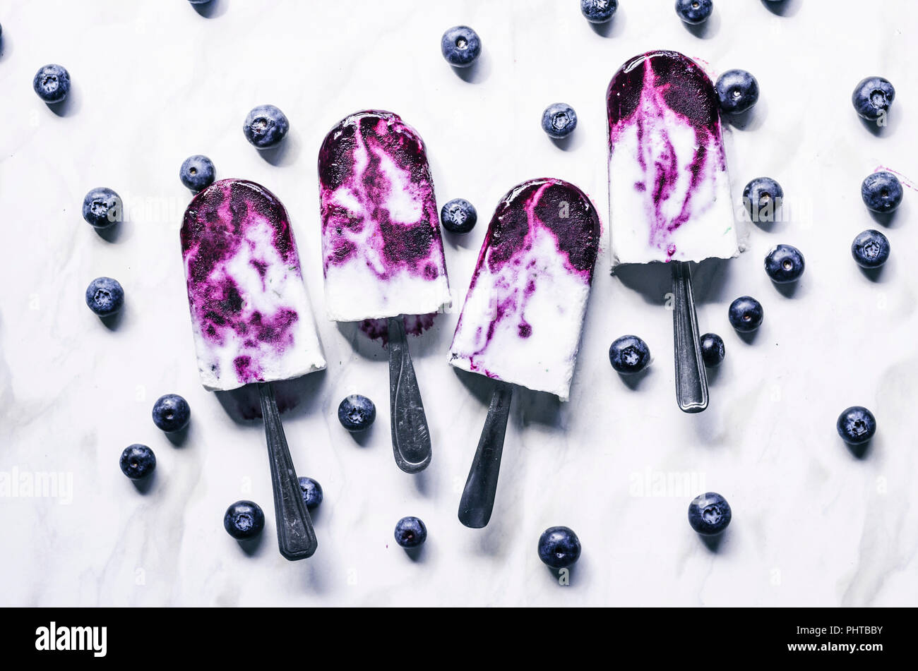 Blueberry coconut milk swirl popsicles with lime on marble background Stock Photo