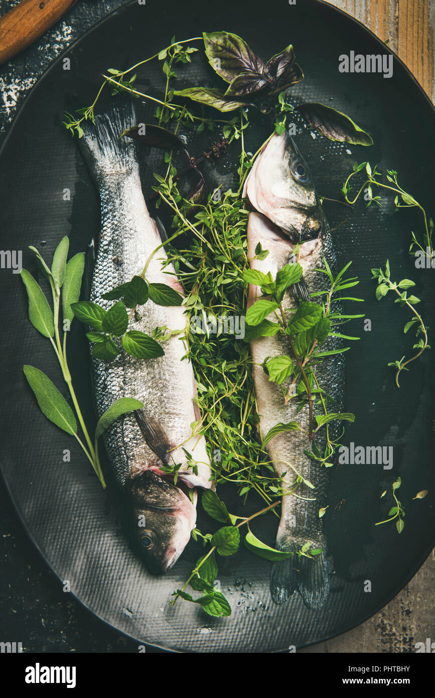 Cooking fish dinner. Flatlay of raw uncooked sea bass fish with herbs
