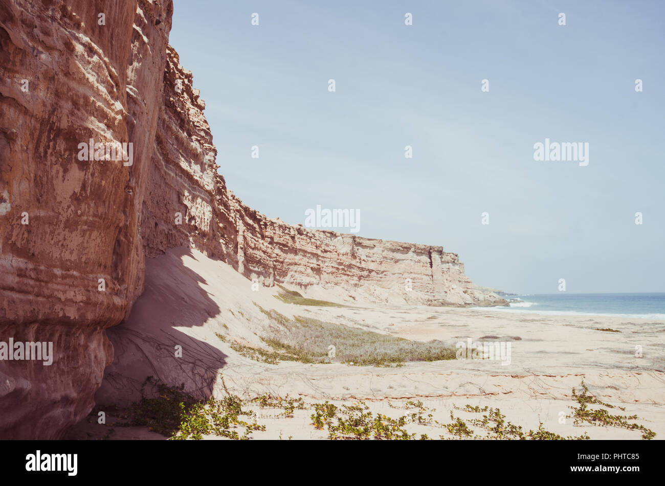 Towering red sandstone cliffs at Angola's coast line in the Namib Desert. Stock Photo