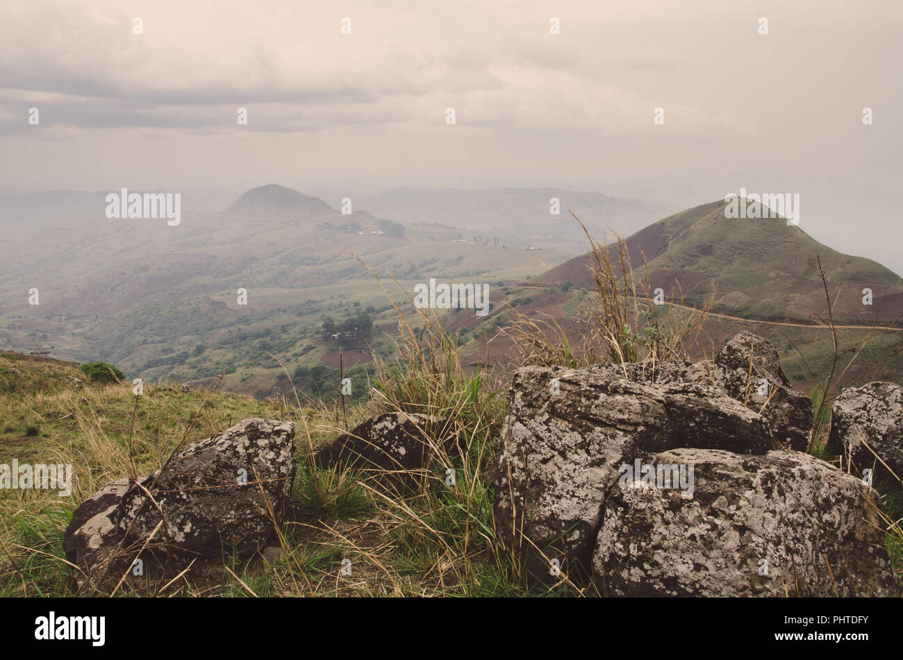 The Ring Road in Cameroon, Africa with soft hills in background and large rocks in foreground on overcast day. Stock Photo