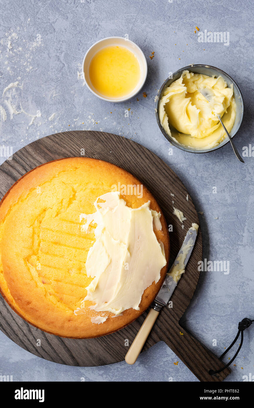 A round homemade orange cake partially spread with butter icing. Stock Photo