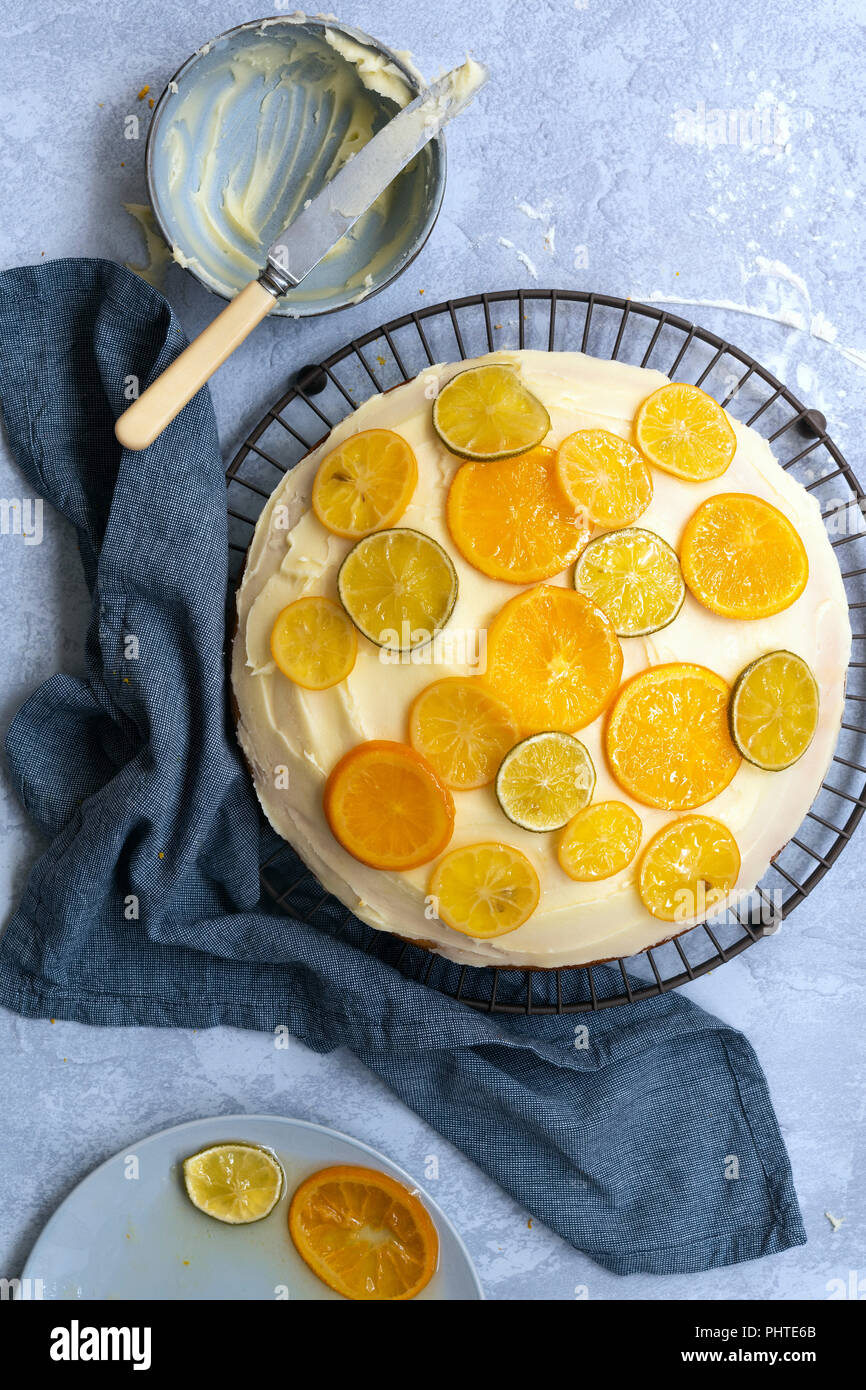 Homemade orange cake spread with butter icing and decorated with slices of candied citrus. Stock Photo