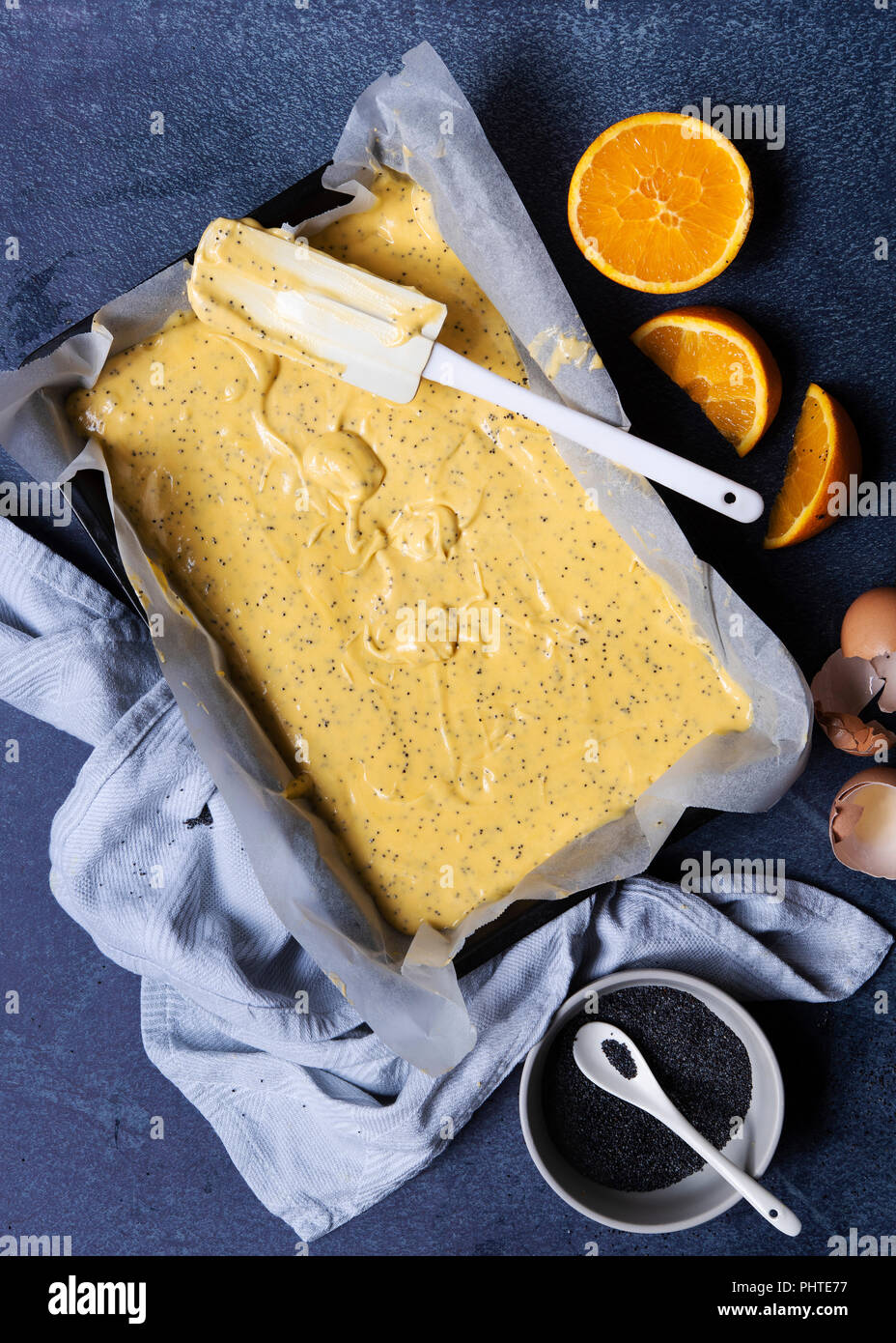 Orange poppy seed cake batter in tin with oranges and a bowl of poppy seeds Stock Photo Alamy