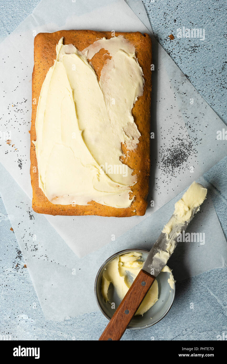 Orange and poppy seed cake partially spread with butter icing. Stock Photo