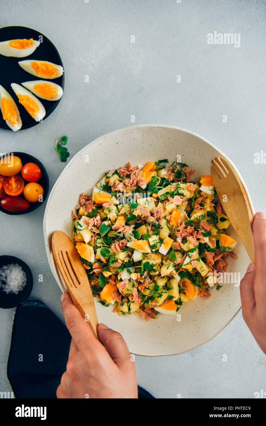 Hands stirring potato tuna egg salad in a ceramic bowl using wooden spoons Stock Photo Alamy