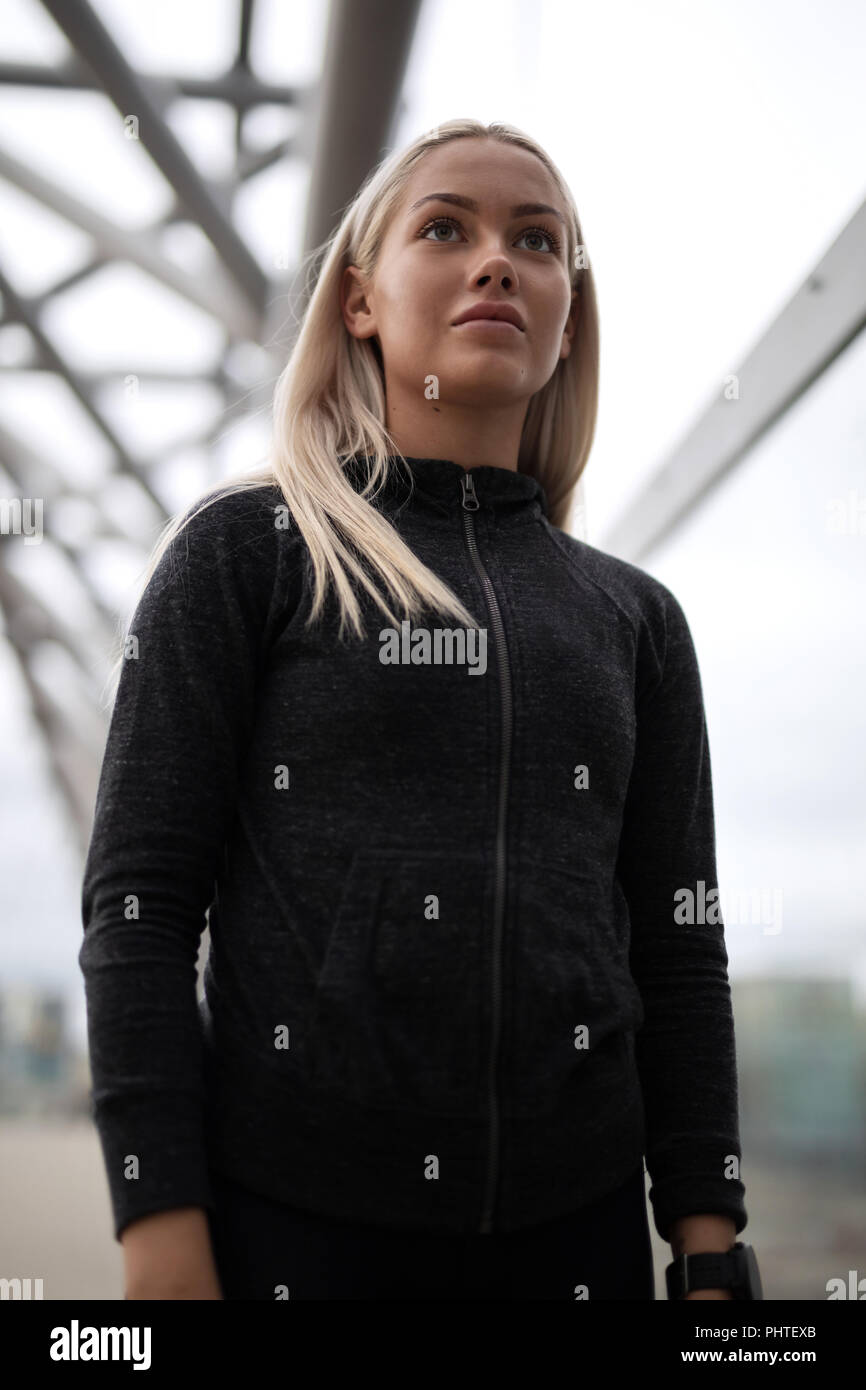 Urban scandinavian woman in workout outfit standing on a bridge Stock Photo