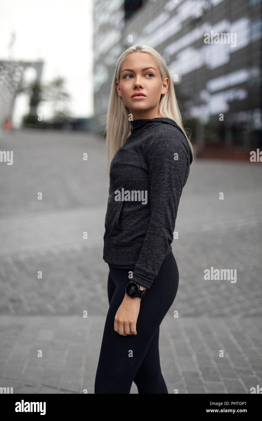 Urban scandinavian woman in workout outfit standing in the city Stock Photo