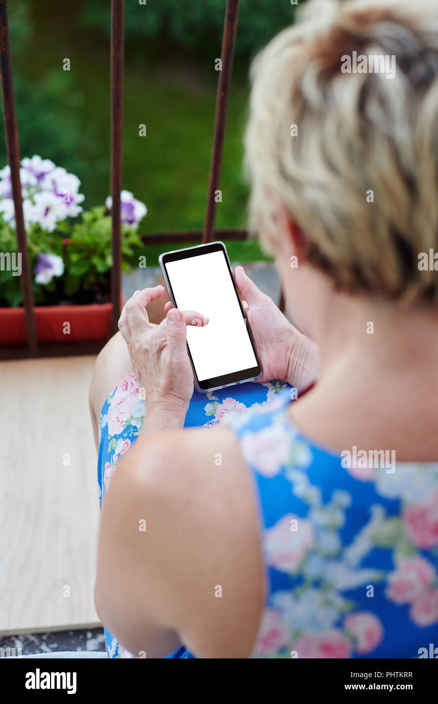 Anonymous woman using smartphone on balcony Stock Photo