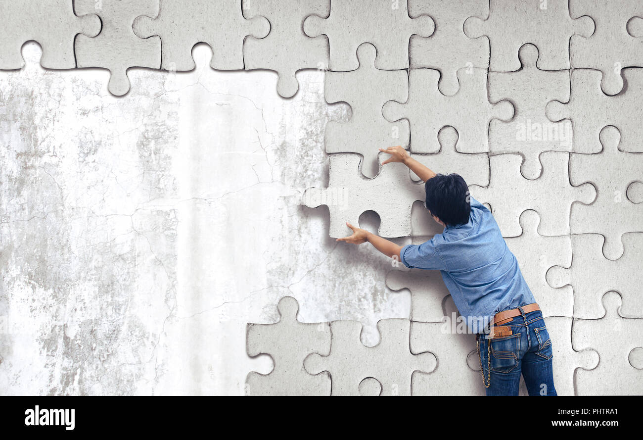 Man making a puzzle on the wall.  empty wall with space for text Stock Photo