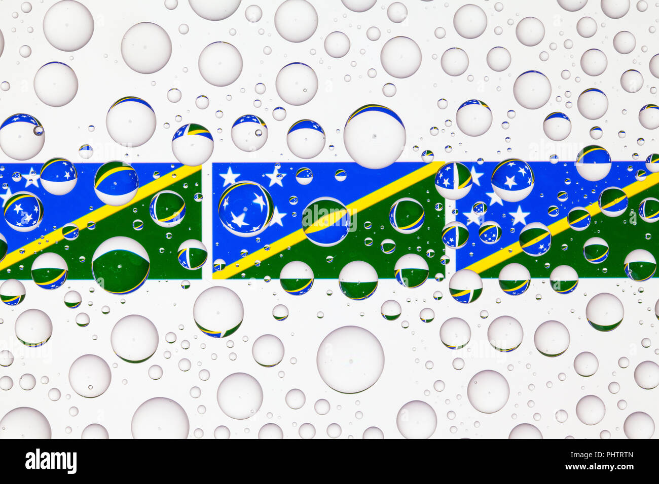 Flags of Solomon Islands behind a glass covered with raindrops. 3D ...