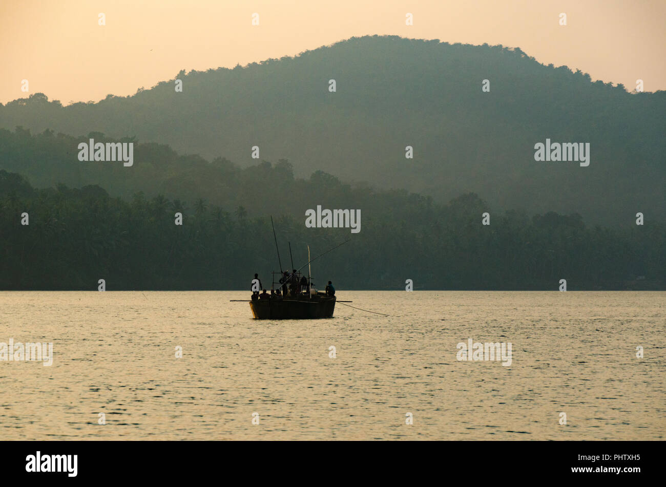A lone sand extraction boat working at dusk on the Mandovi River near Volvoi, Goa, India Stock Photo