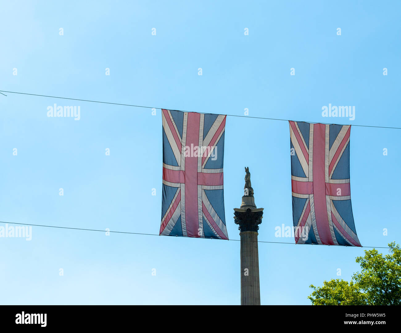 View of Nelson's Column through two Union Jacks against a clear blue sky. Stock Photo