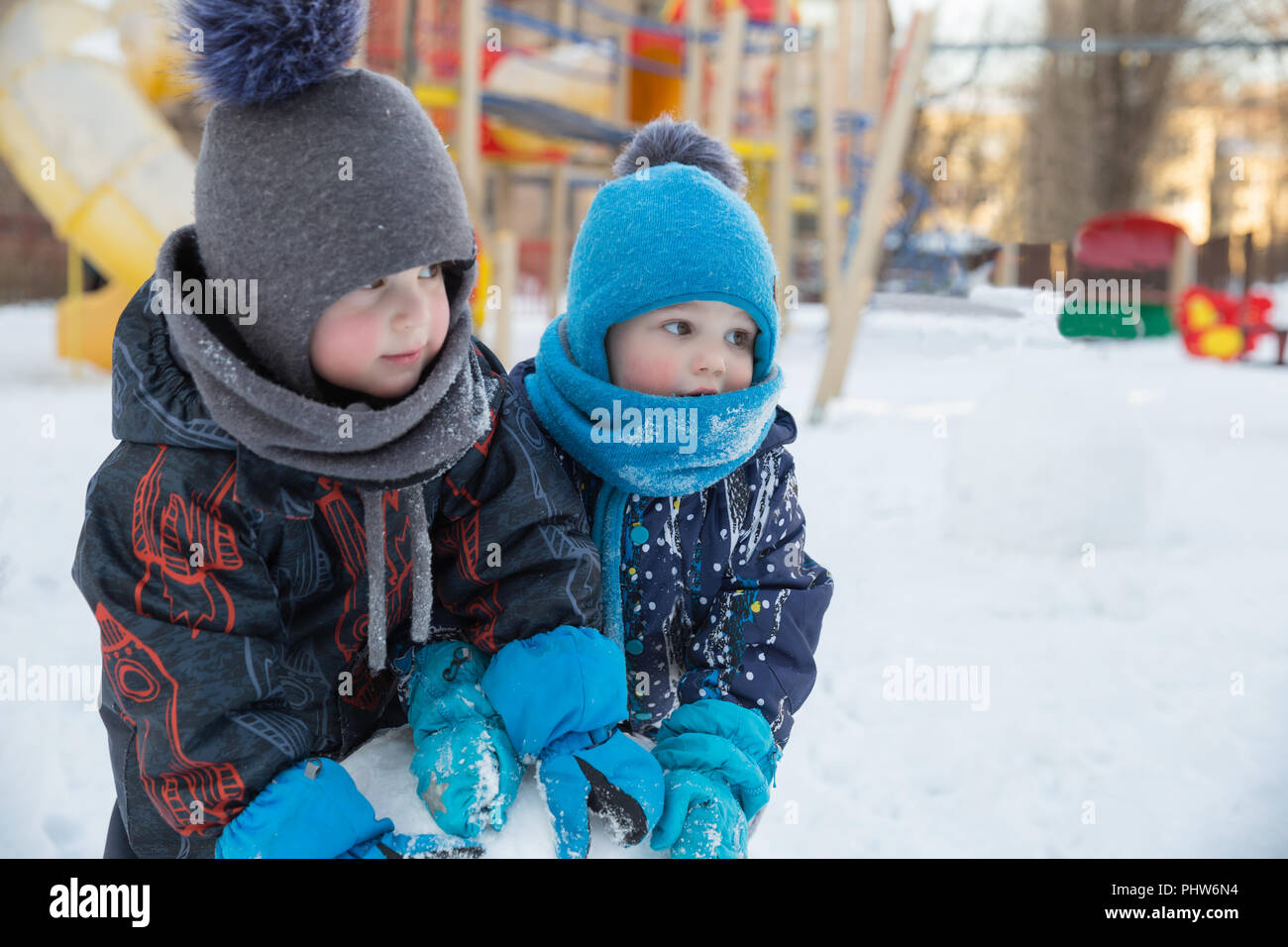 Two cute children boys in warm clothes in winter play in