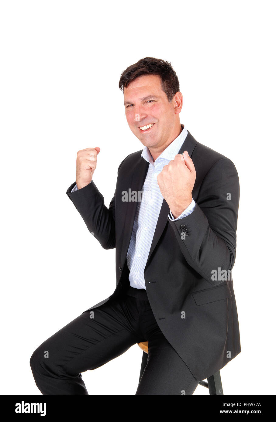 Man sitting on chair with hands in fist, victory Stock Photo