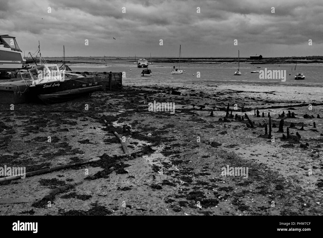 Mud flats and boats that are beached at West Mersea island in Essex, England at low tide. Stock Photo