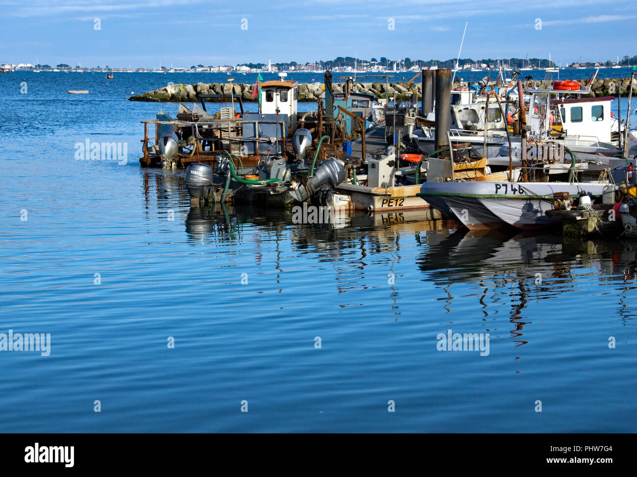 Poole, Dorset, England, Small fishing and lobster boats moored on a jetty at Poole harbour at the end of a days fishing. Calm water all around Stock Photo