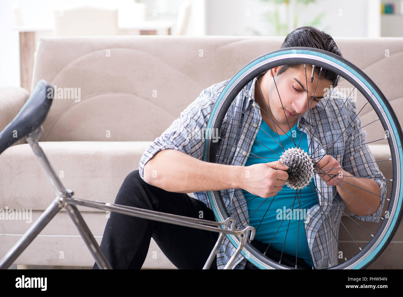 Young man repairing bicycle at home Stock Photo - Alamy