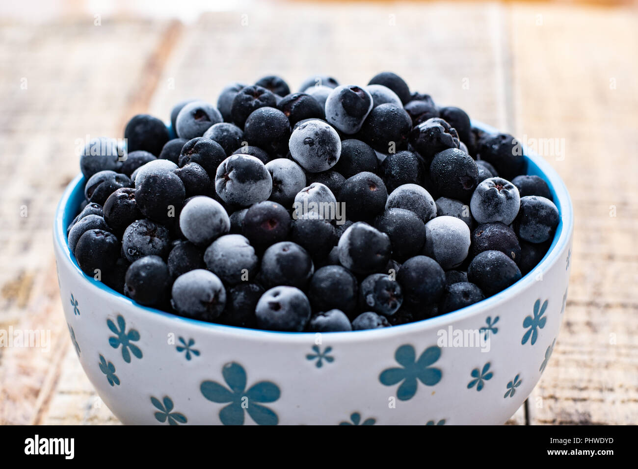 White bowl full with frozen aronia berries Stock Photo
