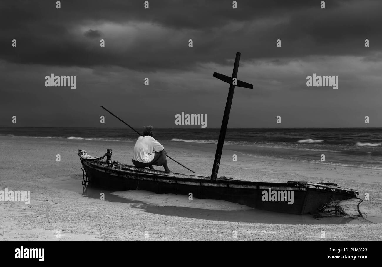 Unidentified old man on wereck boat on the beach with storm clou Stock Photo