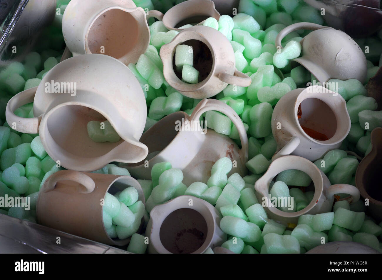 Pale white unglazed pot jugs in a box packed with green polystyrene packing material Stock Photo