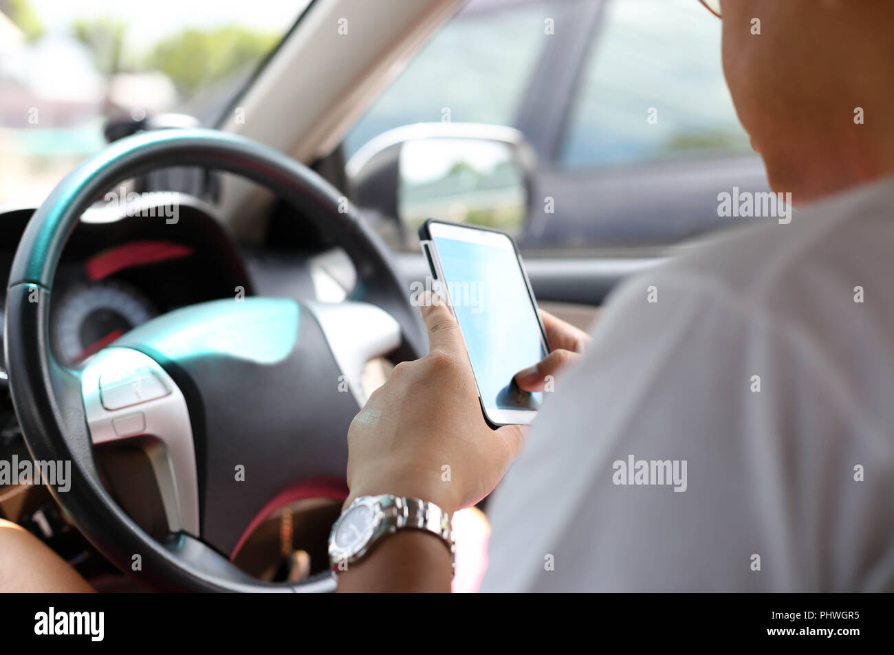 Unidentified man using smart phone while driving on the road Stock Photo
