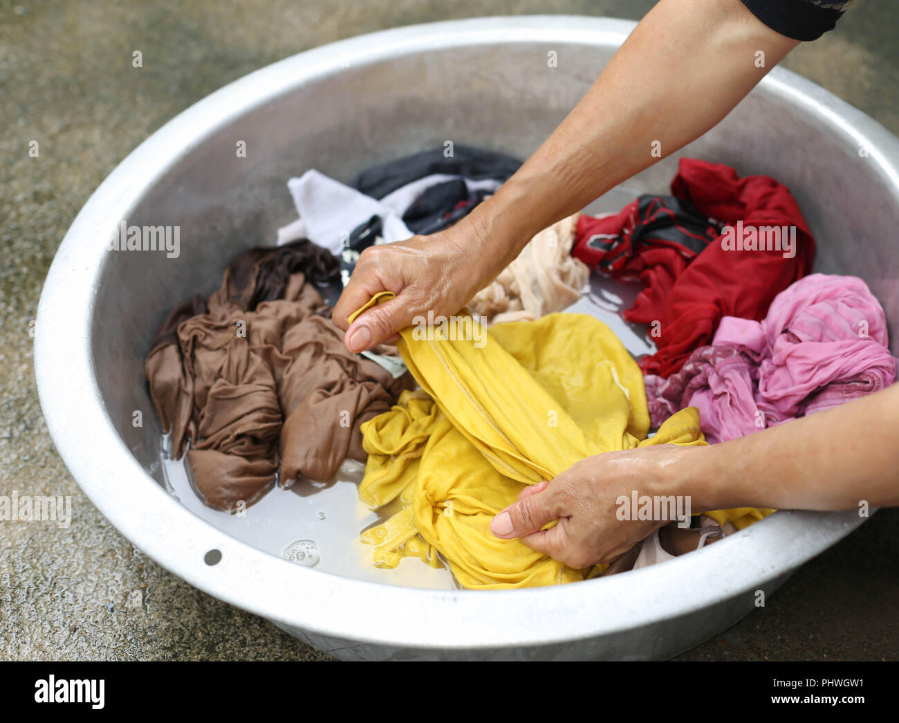 Hands wash stain of dirty clothes in big bowl Stock Photo