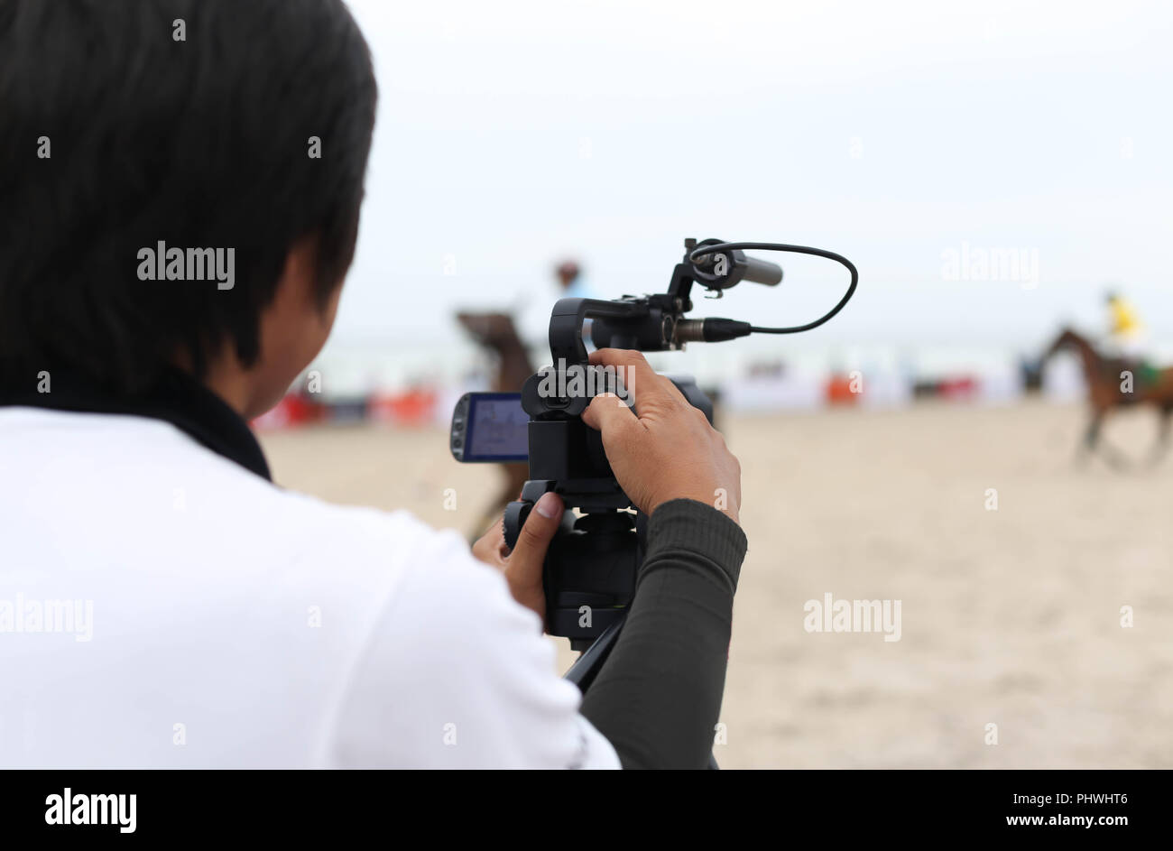 Man holding camcorder as working recording on a beach Polo Tournament