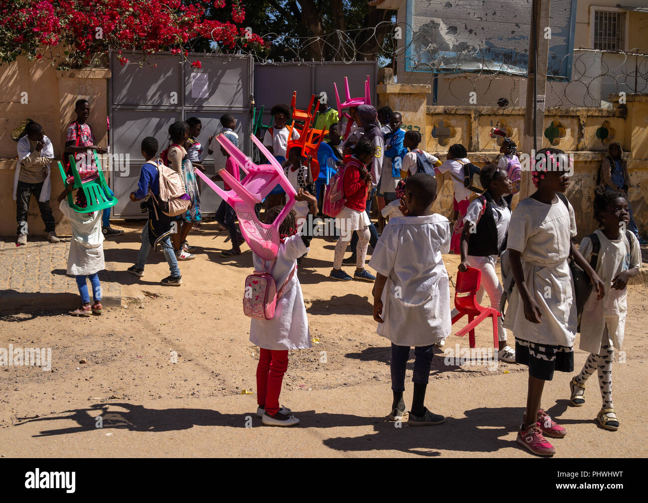 Angolan children carrying her own chairs to go to school, Huila