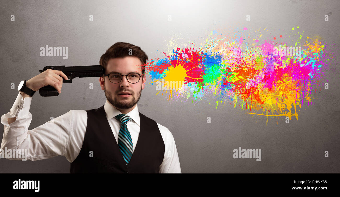 Man shoots his head with gun and colorful splotch are coming out from his head Stock Photo