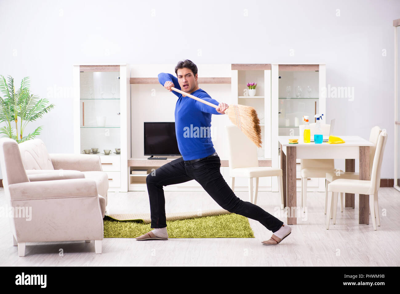 Young man cleaning floor with broom Stock Photo