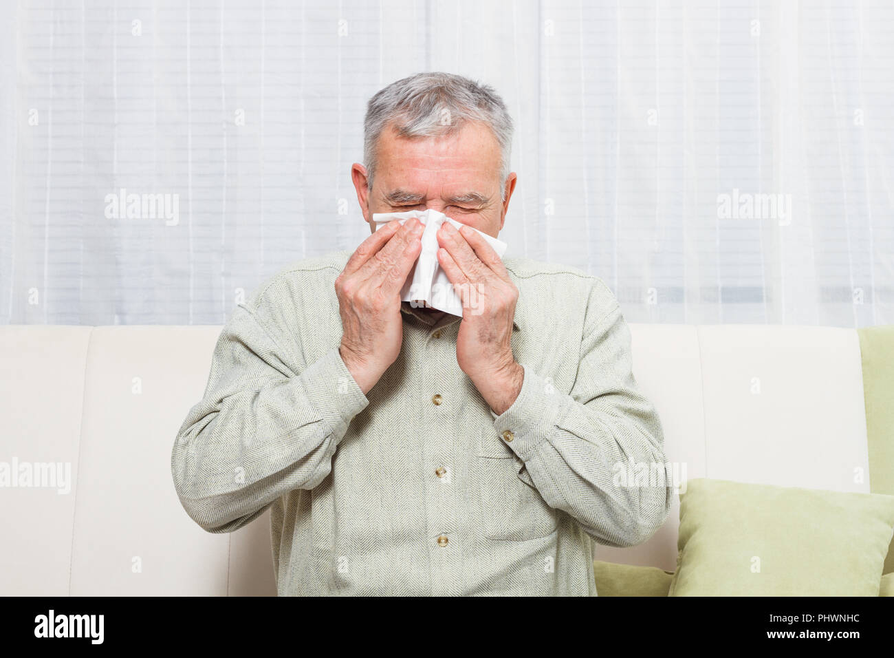 Senior man is sneezing into handkerchief. Stock Photo