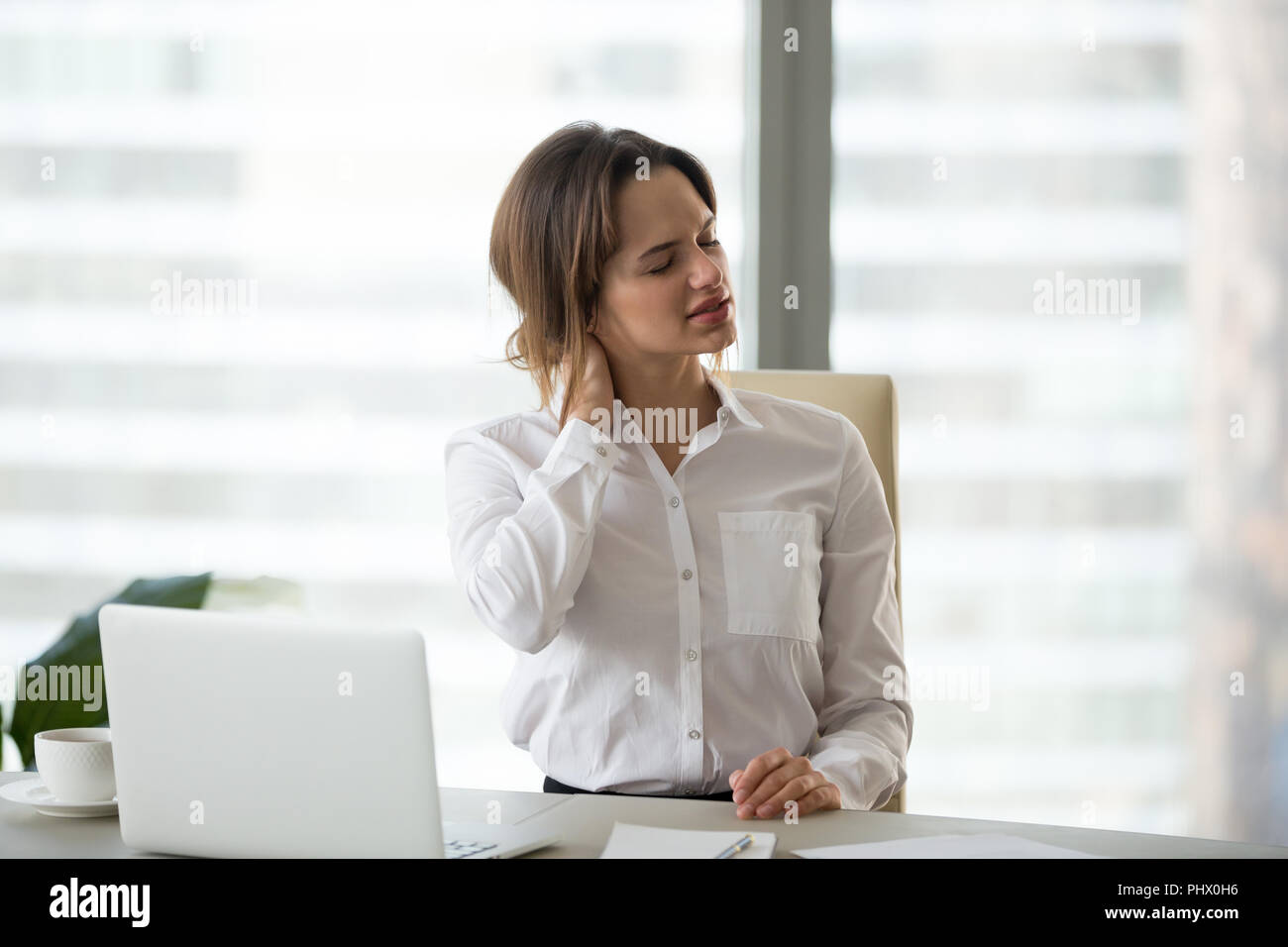Businesswoman massaging neck muscles to relieve pain after seden Stock Photo
