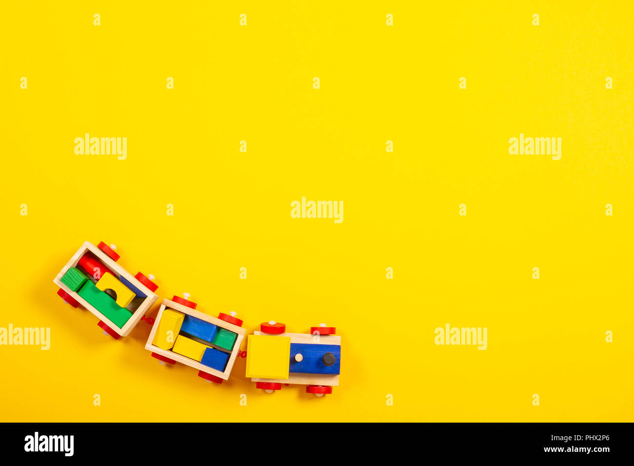 Wooden toy train with colorful blocks on yellow background Stock Photo