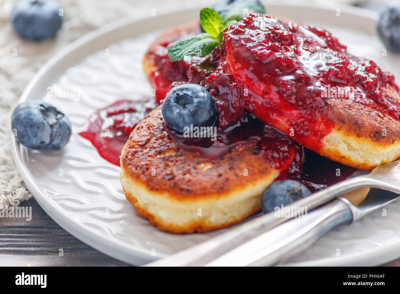 Curd pancakes with berry sauce on a plate. Stock Photo
