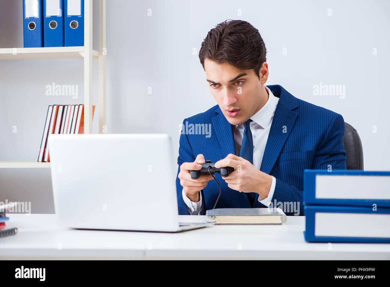 Young handsome businessman playing computer games at work office Stock