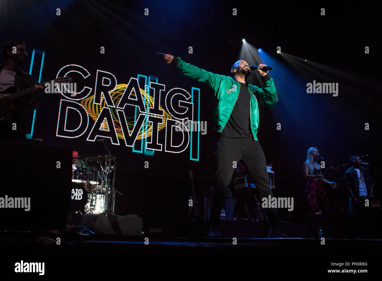 Northampton Cricket Ground, UK. 1st Sept 2018. Craig David performing on stage at Northampton Cricket Ground on 1st September 2018 with his logo on screen behind him. Wearing black trousers, shirt and green designer bomber jacket Credit: Kev Wise Images/Alamy Live News Stock Photo