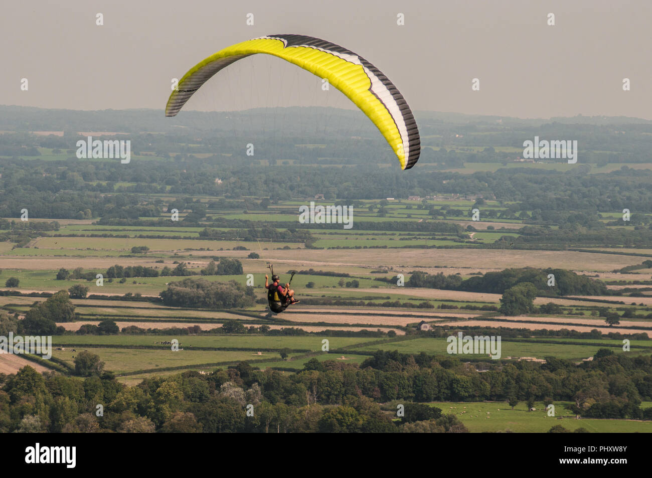Firle, Lewes, East Sussex, UK..3 September 2018..Paraglider pilot  flying into the morning NW breeze over the Sussex countryside  near Firle Beacon in the South Downs. . Stock Photo