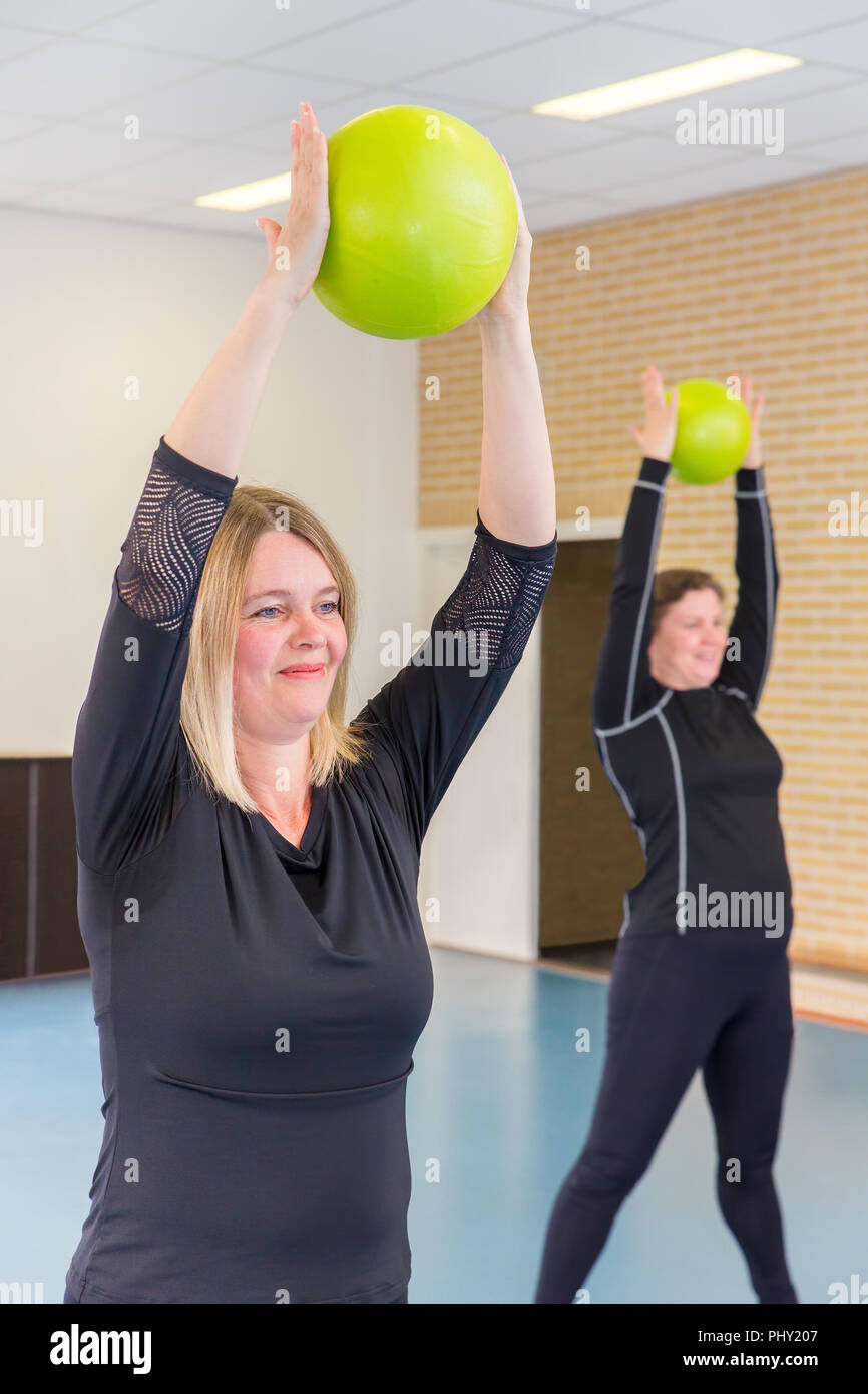 Two dutch caucasian women exercising with balls in gym class Stock Photo