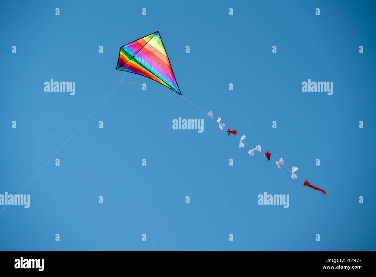 Colorful kite flying against a blue sky. Stock Photo