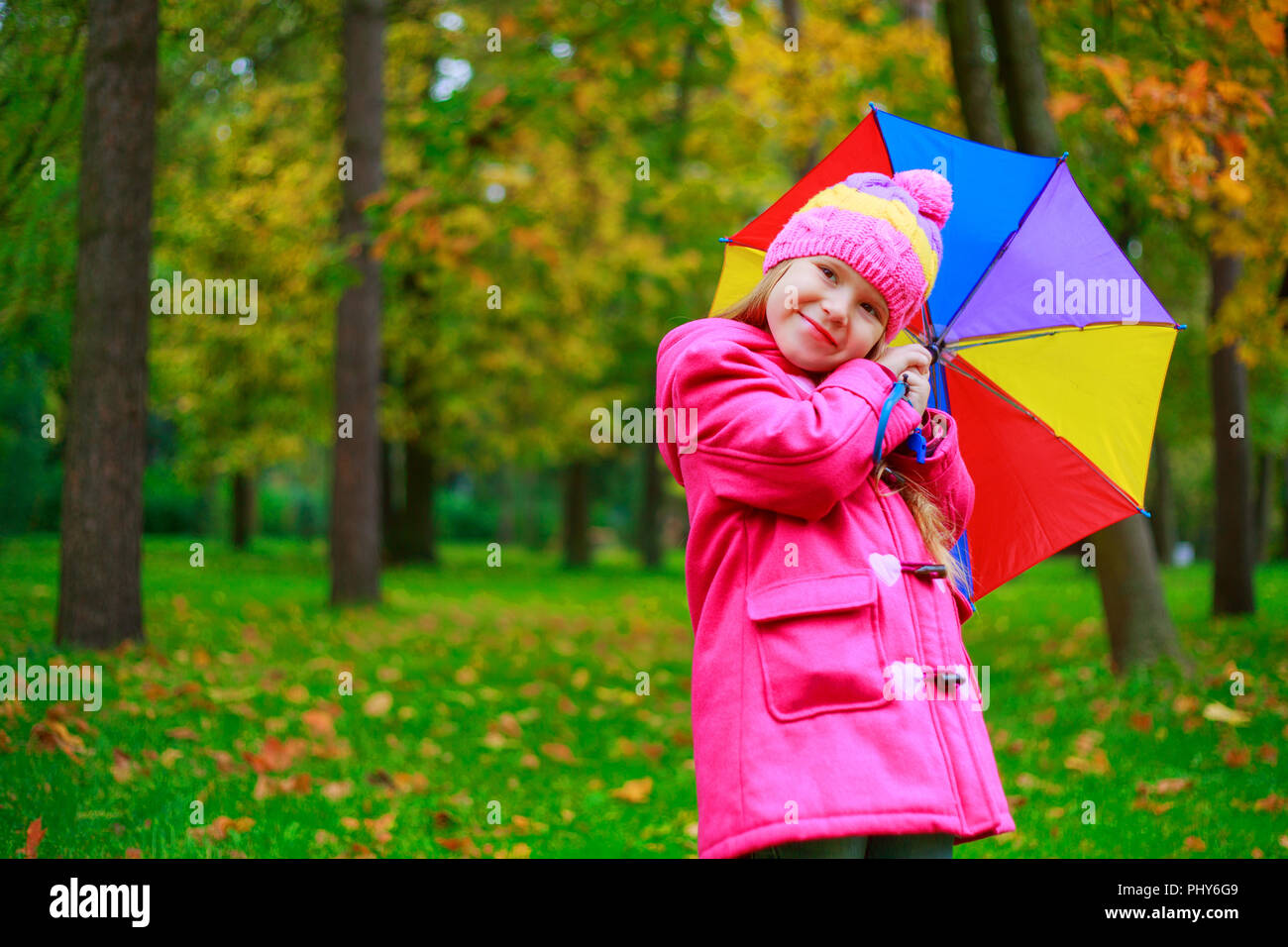 happy little girl with a colorful umbrella outdoor in the autumn park ...