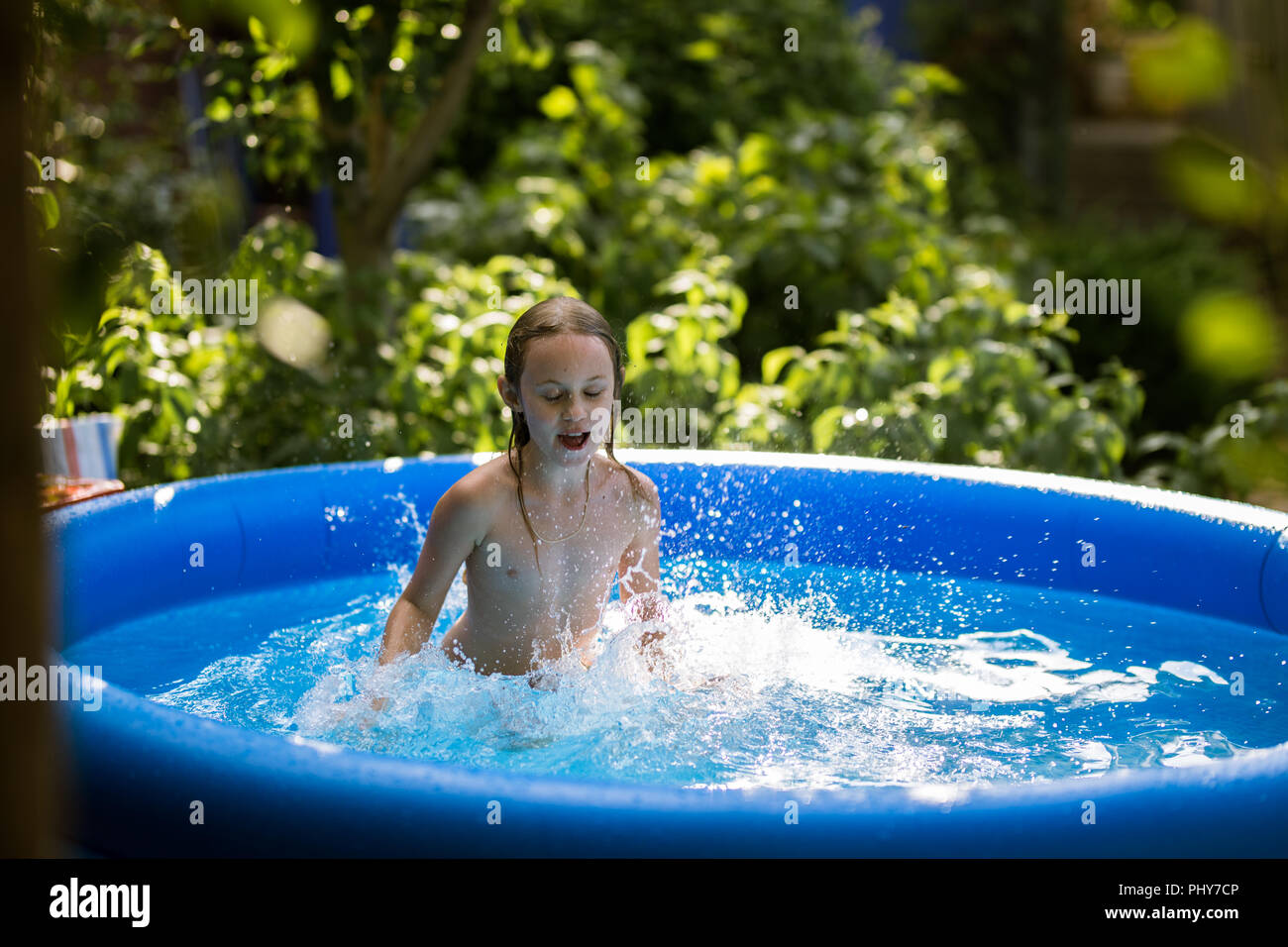 Smiling adorable seven years old girl playing and having fun in inflatable pool. Stock Photo