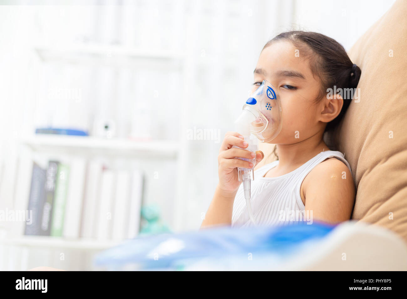 Cute Asian child patient inhalation therapy by the mask of inhaler with soft stream smoke from