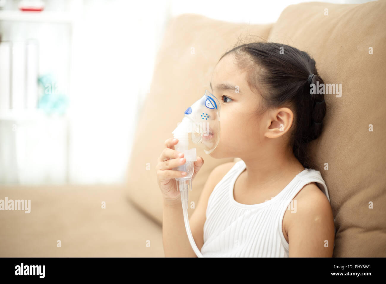 Cute Asian child patient inhalation therapy by the mask of inhaler with soft stream smoke from