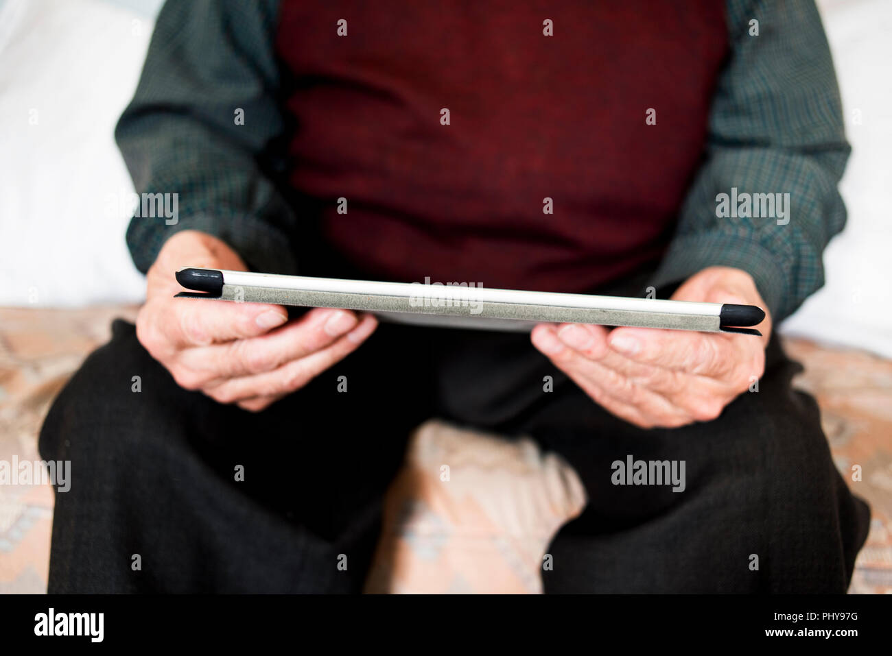 closeup of an old caucasian man sitting in a couch using a tablet or an e-reader Stock Photo