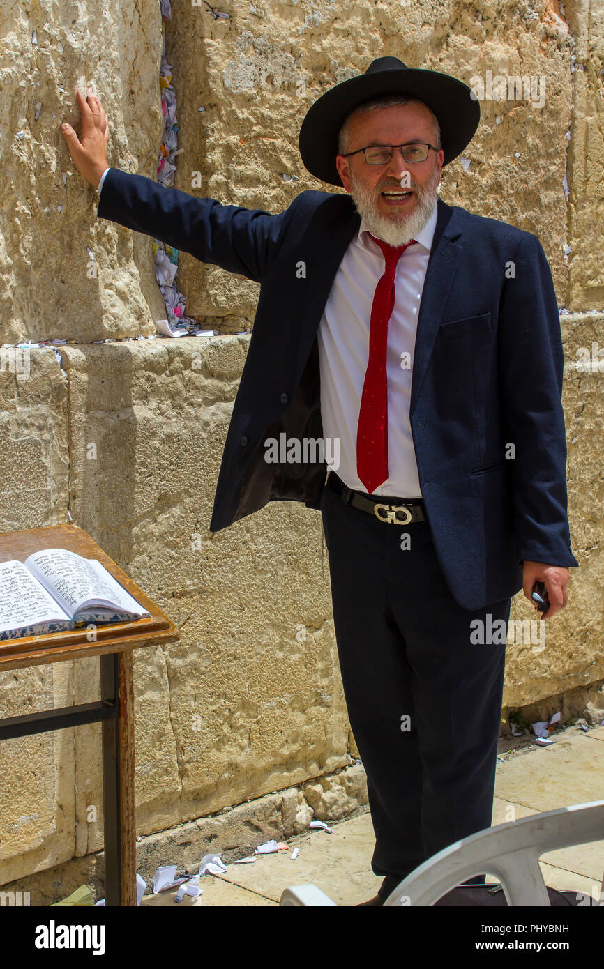 10 May 2018 An Orthodox Jewish male in a traditional dark suit and hat  touching the Western Wall in jerusalem Israel Stock Photo