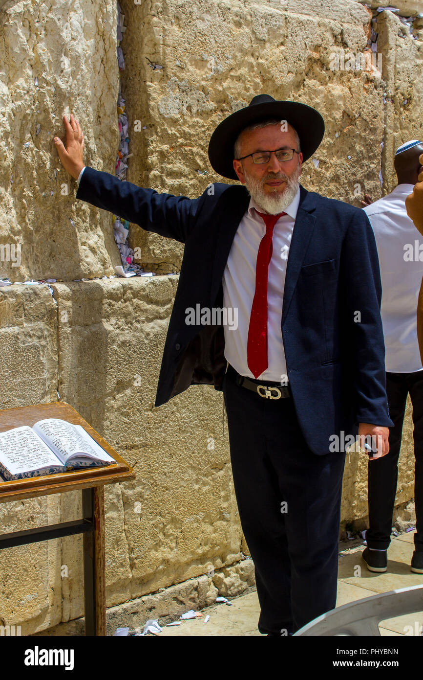 10 May 2018 An Orthodox Jewish male in a traditional dark suit and hat  touching the Western Wall in jerusalem Israel Stock Photo