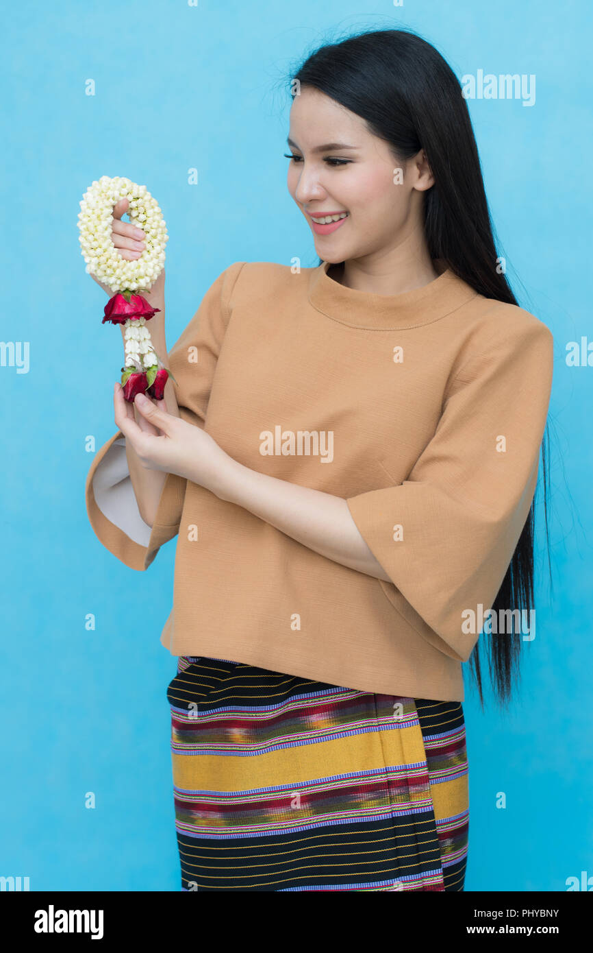 Portrait of asian young girl in traditional thai dress and holding jasmine garland isolated on blue sky background. Cotton dress Stock Photo